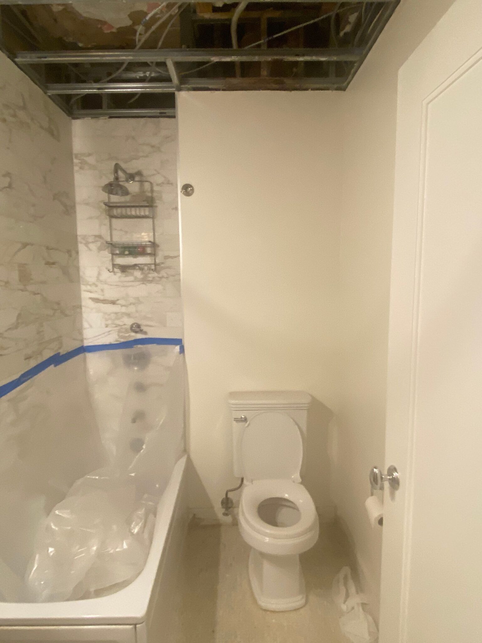 Almost Completed bathroom renovation after water damage, showcasing a new bathtub, toilet, and fresh wall finishes.