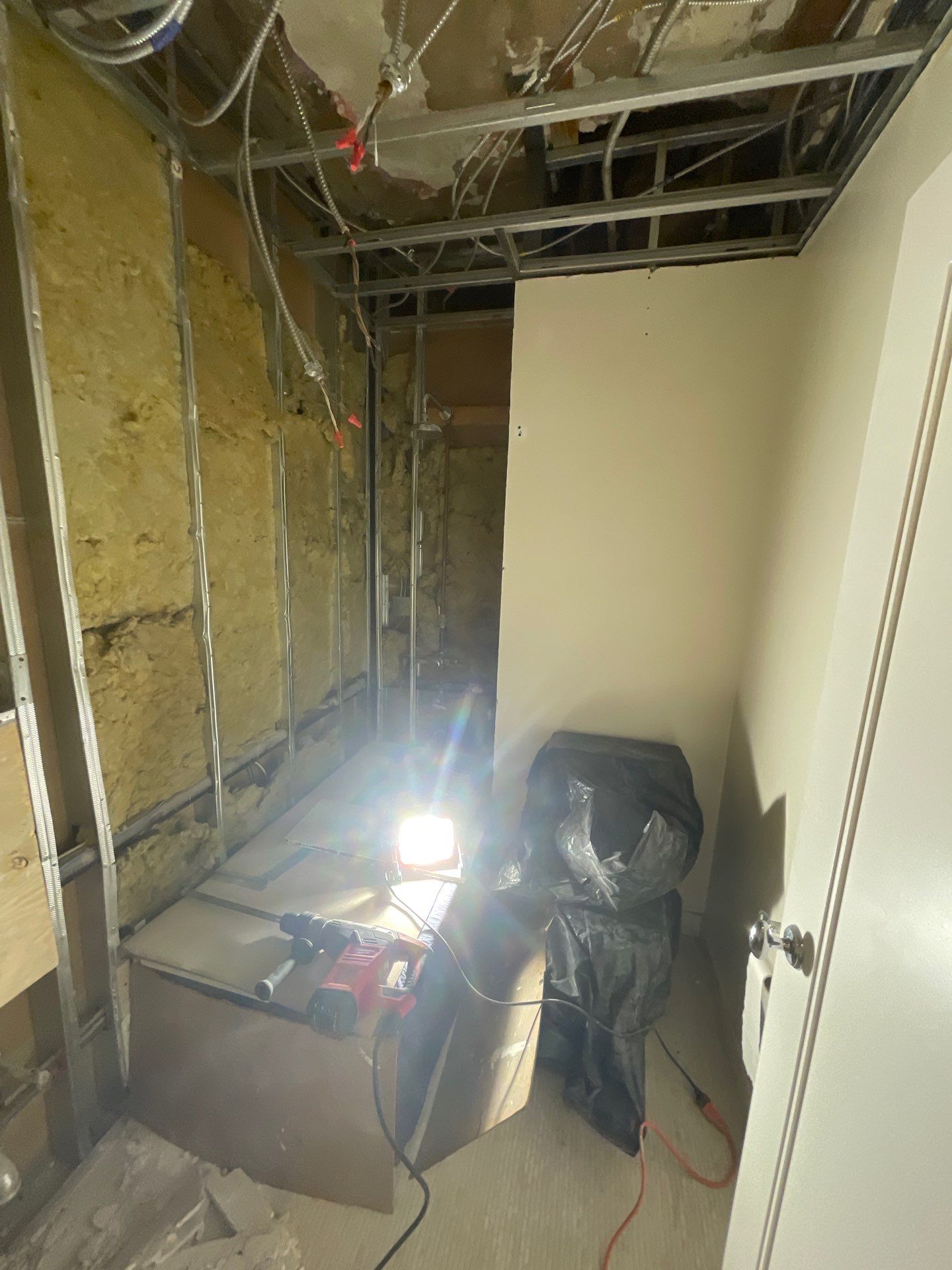 Demolition phase of a bathroom renovation due to water damage, featuring construction tools and exposed framework.