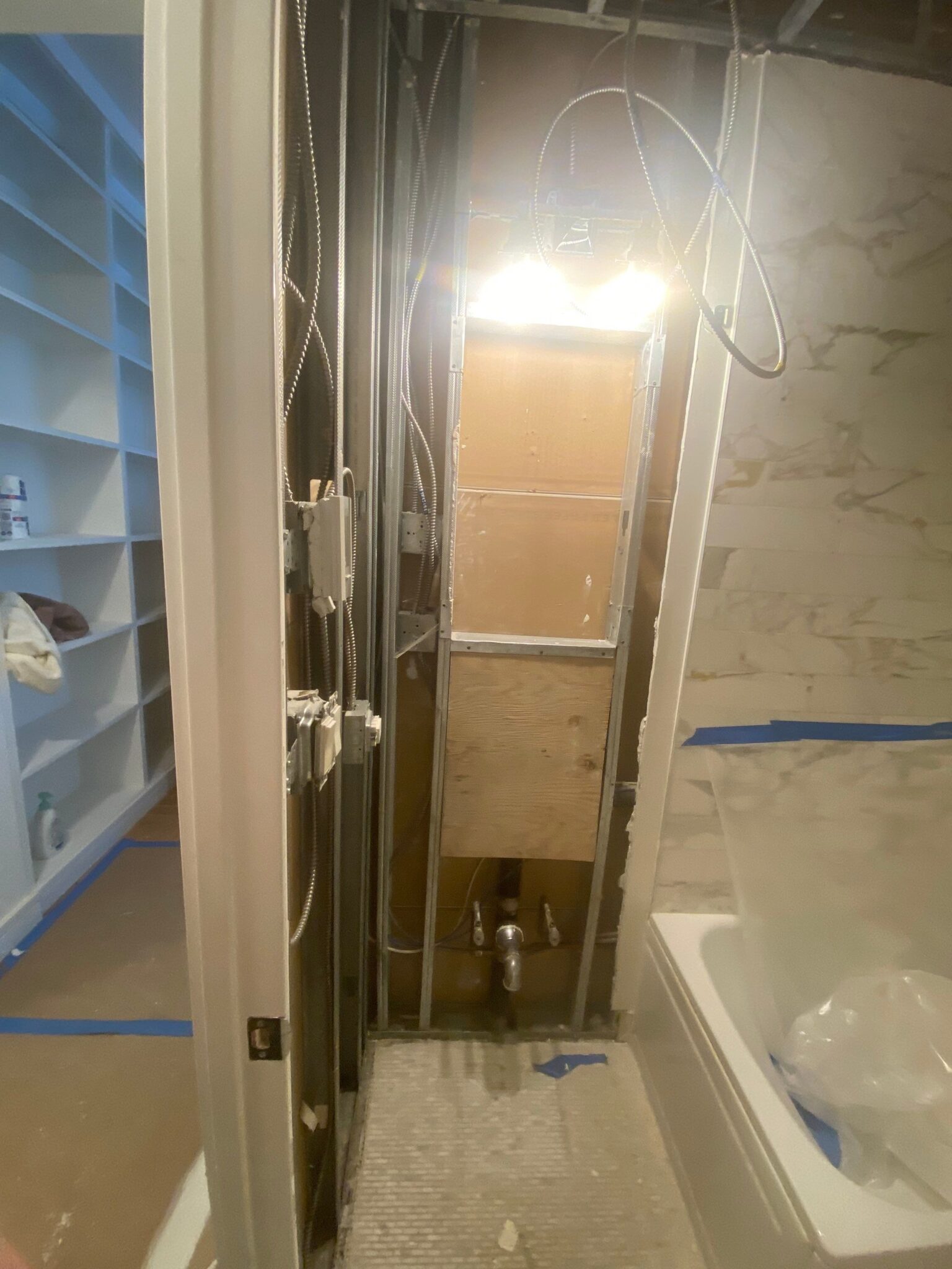 In-progress bathroom renovation with exposed plumbing and wiring after water damage repairs.